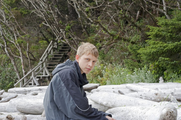Fototapeta premium Teenage Boy sitting on Driftwood