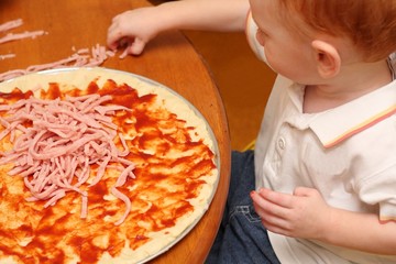 Young boy preparing homemade pizza
