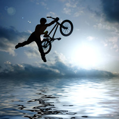 silhouette of boy with bicycle jumping in air