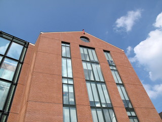 Fototapeta na wymiar Immeuble de brique rouge et verre, ciel bleu.