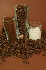 Kaffebohnen, Kaffepulver und Milch in Schnapsgläsern - hoch schr