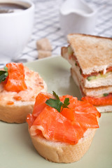 three salmon sandwiches with cup of strong coffee
