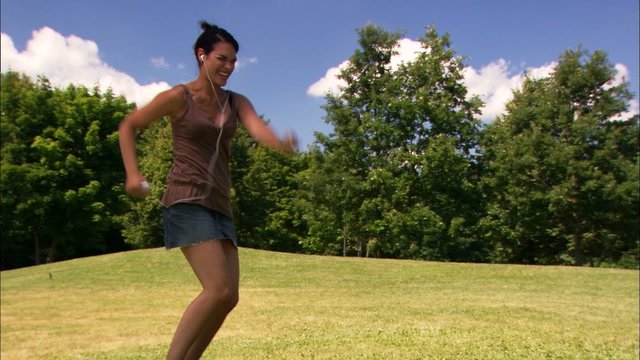 junge frau musik h&ouml;rend, tanzend und springend auf einer wiese