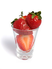 Strawberries cut in a glass on white background