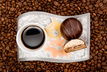 Coffee cup with sweets on beans background