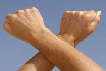Crossed fists isolated against the blue sky