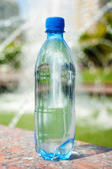 Blue bottle with water against blurred fountain