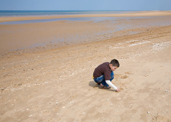 small boy drawing in the sand, low tide