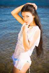 Fototapeta na wymiar Beautiful sensual brunette girl standing in blue water