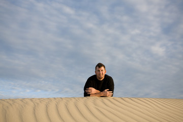 Fototapeta na wymiar Handsome man laying down on the desert sand