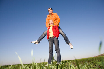 Naklejka na ściany i meble Happy smiling couple jumping in blue sky