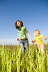 Fototapeta premium Happy woman and girl making exercises on field