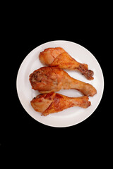 Three roasted chicken legs on the plate.