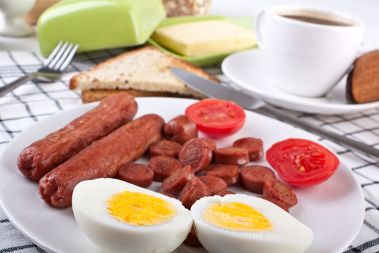 traditional breakfast with fried sausages,a boiled egg and a cup
