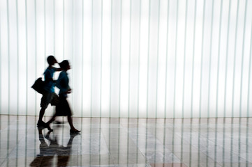 Silhouette of a person walking against a white patterned backgro