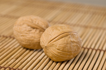 Two walnuts on bamboo mat.