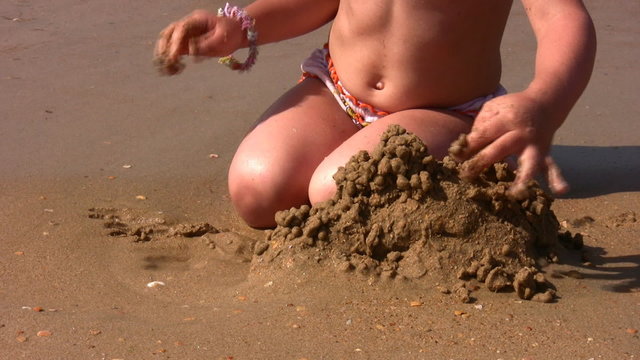 hands of little girl play with sand on beach