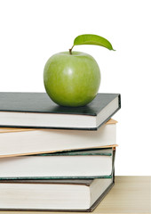 Green apple on pile of books