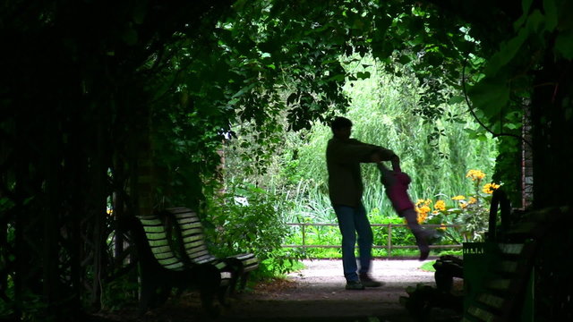 father rotate girl silhouette in plant tunnel
