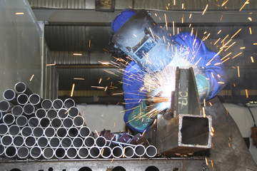 Man welding pipes on a production line