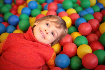 little girl lies on multi-coloured plastic spheres