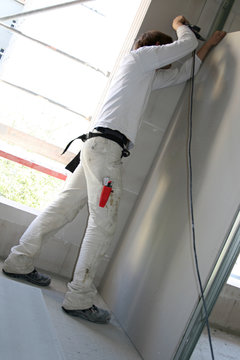 Trockenbauer befestigt Regipswand