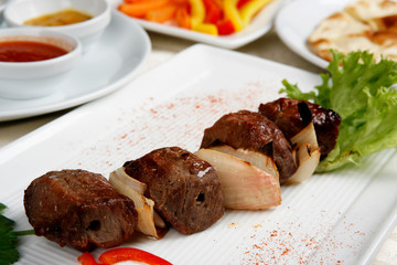 Appetizing shish kebab with tomatoes and greens