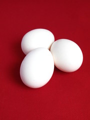 Group of three eggs on red background