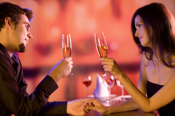 Young couple sharing champagne glasses in restaurant