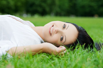 Sexy smiling woman laying on grass