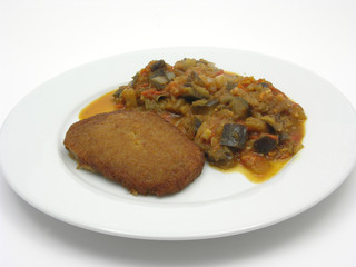 Ppaniertes Tofuschnitzel mit gebratenem Gemüse auf weißem Teller