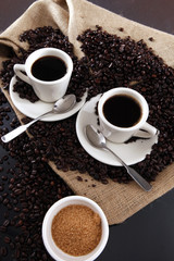 Cups of fresh brewed coffee and coffee grains from a sisal sack