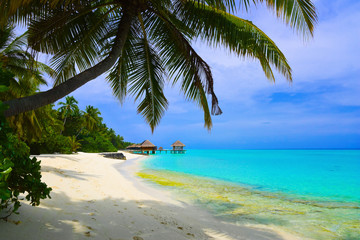 Fototapeta na wymiar Water bungalows on beach of tropical island