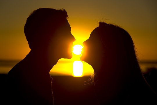 A couple about to kiss at sunset