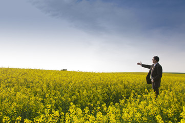 Manager im Rapsfeld streckt den Arm aus