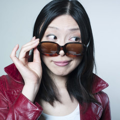 femme curieuse regardant par dessus ses lunettes de soleil