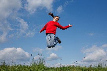 Girl jumping, running against blue sky