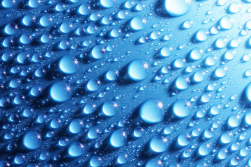Shiny water drops on metallic blue surface