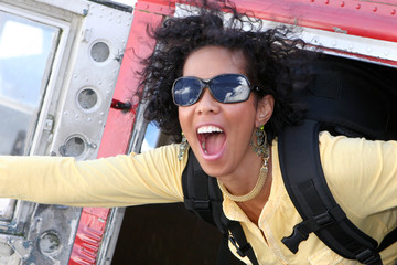 Excited young woman jumping out of plane