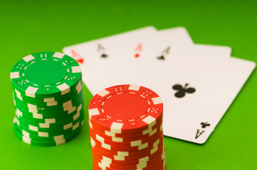 Casino chips and four aces against green background