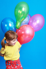 Fototapeta na wymiar little girl holding colorful balloons on a blue background