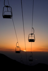 Ski lift chairs on sunset