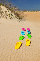 Colorful Summer Flip Flops on beach with sand and lighthouse