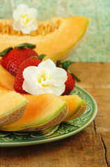 Sliced Cantaloupe, Strawberries, and Flowers.