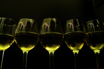 row of white wine glasses, on dark background
