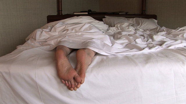 Woman lying in bed and stretching her feet