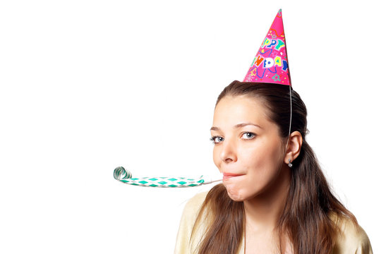 Young pretty woman in birthday cap with noisemaker