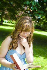 Student reading a book in a park