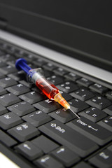 Seringue posée sur un clavier d'ordinateur
