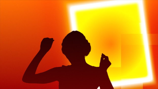 Silhouette of a woman dancing against orange background